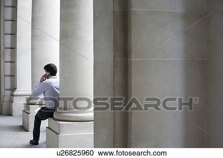 Businessman on cell phone outside building sitting on pillar View Large Photo Image Stock Image - Businessman on cell phone outside building sitting on pillar. Fotosearch