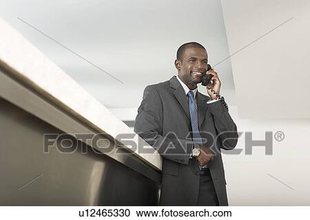 Stock Image - Businessman on Telephone at Counter. Fotosearch