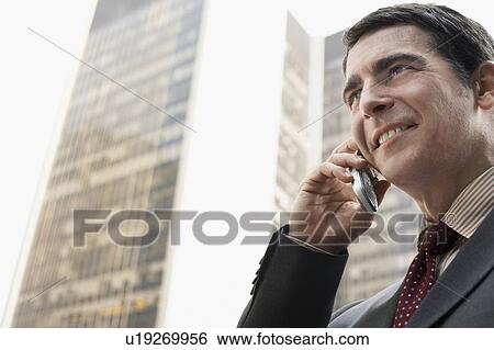 Stock Photograph - Businessman outdoors using cell phone. Fotosearch