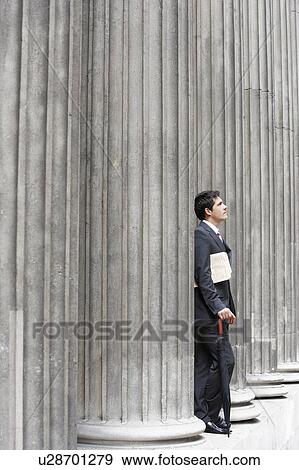 Stock Photo - Businessman outside building looking up at sky. Fotosearch