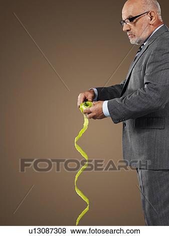Stock Photo - Businessman Pealing an Apple, side view. Fotosearch