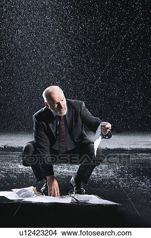 Businessman Picking up soaked Paperwork during downpour View Large Photo Image Picture - Businessman Picking up soaked Paperwork during downpour. Fotosearch