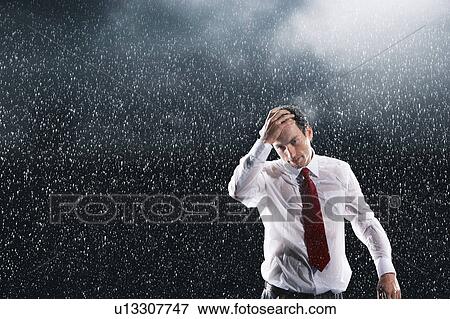 Stock Photo - Businessman running hands through wet hair, standing in the Rain. Fotosearch