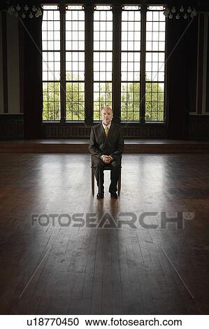 Stock Image - Businessman Sitting in Large, Empty Room. Fotosearch