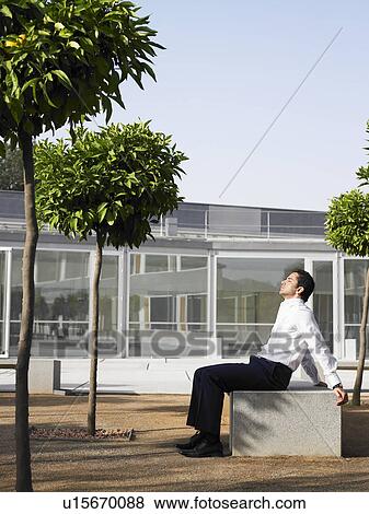 Businessman sitting in plaza relaxing in sunshine View Large Photo Image Stock Photo - Businessman sitting in plaza relaxing in sunshine. Fotosearch