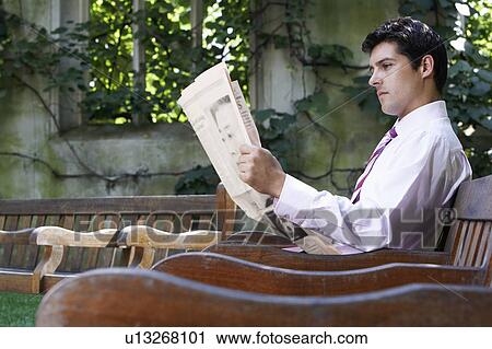 Businessman sitting on bench in park garden reading paper View Large Photo Image Stock Image - Businessman sitting on bench in park garden reading paper. Fotosearch