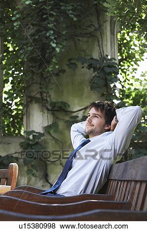 Stock Photo - Businessman sitting on park bench relaxing. Fotosearch