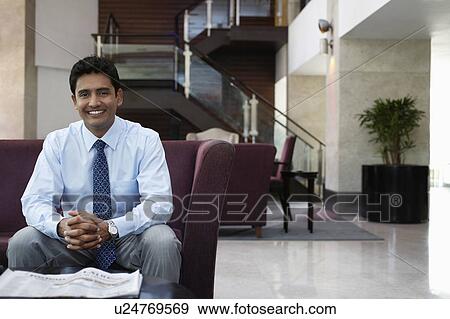 Stock Photo - Businessman sitting on sofa, portrait. Fotosearch