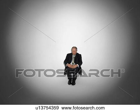 Businessman sitting under Spotlight View Large Photo Image Stock Photo - Businessman sitting under Spotlight. Fotosearch