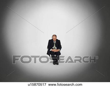 Stock Photo - Businessman sitting under the spotlight. Fotosearch
