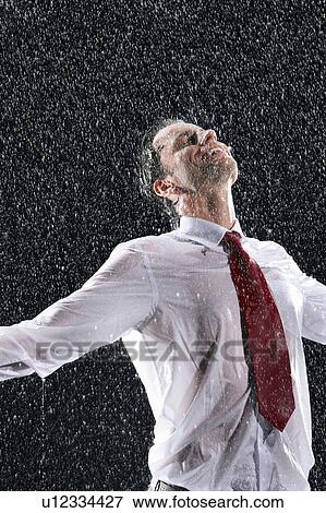 Businessman standing, arms spread facing incoming rain View Large Photo Image Stock Photo - Businessman standing, arms spread facing incoming rain. Fotosearch