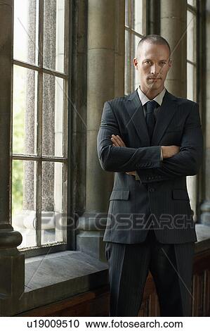 Businessman Standing by Window, arms folded View Large Photo Image Stock Image - Businessman Standing by Window, arms folded. Fotosearch