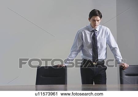 Stock Image - Businessman standing in conference room, portrait. Fotosearch