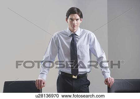 Stock Image - Businessman standing in conference room, portrait. Fotosearch