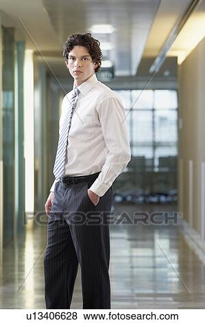 Businessman standing in office corridor, portrait View Large Photo Image Stock Photo - Businessman standing in office corridor, portrait. Fotosearch