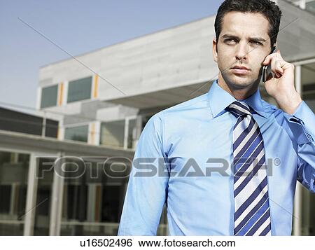 Businessman standing in plaza using cell phone View Large Photo Image Stock Photograph - Businessman standing in plaza using cell phone. Fotosearch