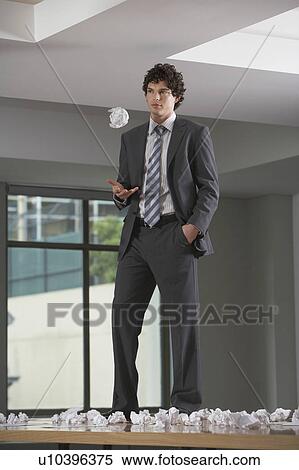 Businessman standing on conference room table with crumpled paper View Large Photo Image Stock Photography - Businessman standing on conference room table with crumpled paper. Fotosearch