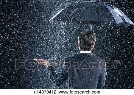 Businessman staying dry under umbrella during downpour, back view View Large Photo Image Stock Image - Businessman staying dry under umbrella during downpour, back view. Fotosearch