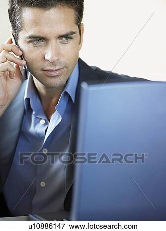Businessman Using Cell Phone and Laptop Indoors View Large Photo Image Stock Photo - Businessman Using Cell Phone and Laptop Indoors. Fotosearch