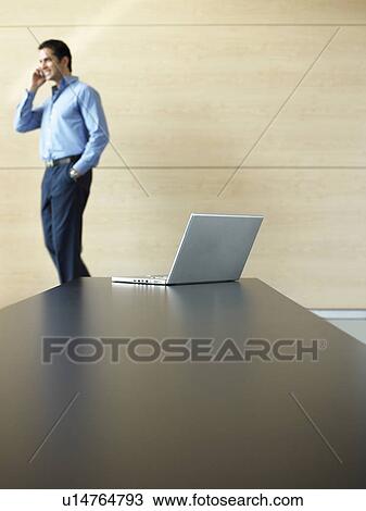 Stock Image - Businessman Using Cell Phone in meeting room. Fotosearch
