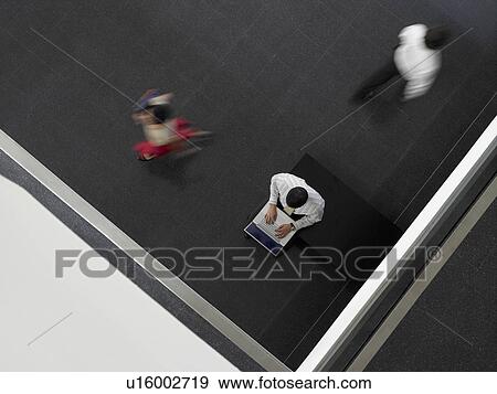 Businessman Using Laptop in entrance hall of building, overhead view View Large Photo Image Stock Photo - Businessman Using Laptop in entrance hall of building, overhead view. Fotosearch