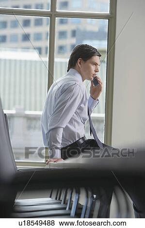 Businessman using mobile phone in office, side view View Large Photo Image Stock Photo - Businessman using mobile phone in office, side view. Fotosearch