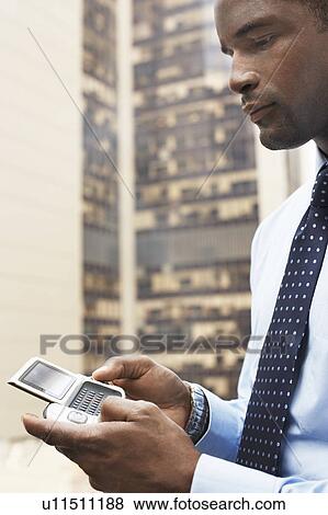 Businessman Using PDA, standing outdoors, side view, cropped View Large Photo Image Stock Photo - Businessman Using PDA, standing outdoors, side view, cropped. Fotosearch