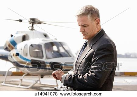 Stock Photo - Businessman waiting at helicopter pad. Fotosearch