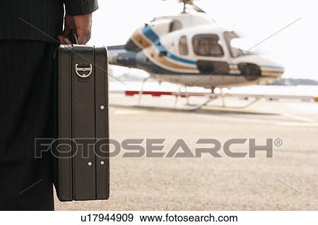 Businessman with briefcase, on helicopter pad View Large Photo Image Stock Photo - Businessman with briefcase, on helicopter pad. Fotosearch