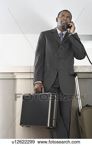 Businessman with luggage on telephone View Large Photo Image Stock Photo - Businessman with luggage on telephone. Fotosearch