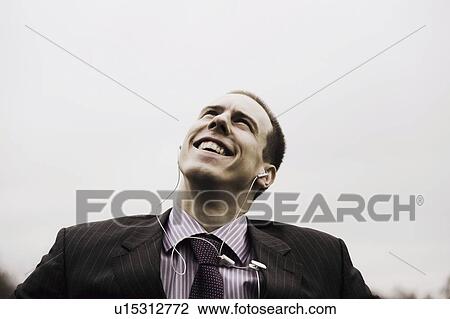 Businessman with MP3 player looks up smiling View Large Photo Image Stock Image - Businessman with MP3 player looks up smiling. Fotosearch
