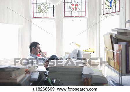 Stock Photo - Businessman works from desk in bay window. Fotosearch