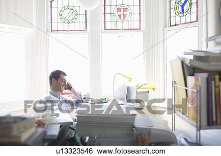 Businessman works from desk in bay window View Large Photo Image Stock Photograph - Businessman works from desk in bay window. Fotosearch