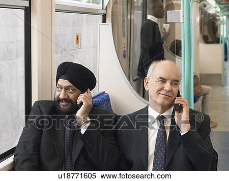 Stock Photography - Businessmen sitting on commuter train, Using Cell Phones. Fotosearch