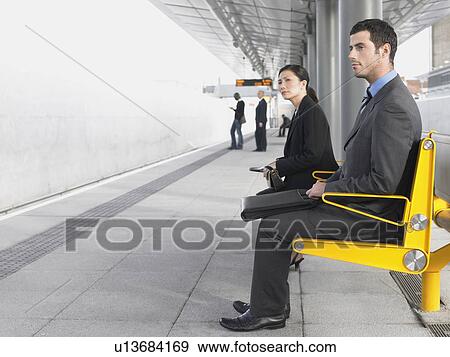 Businesspeople sitting on benches, Waiting at Train Station, side view View Large Photo Image Stock Photo - Businesspeople sitting on benches, Waiting at Train Station, side view. Fotosearch