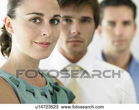 Stock Image - Businesswoman and two businessmen, focus on woman, portrait. Fotosearch