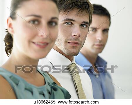 Stock Photography - Businesswoman and two businessmen, focus on man, portrait. Fotosearch