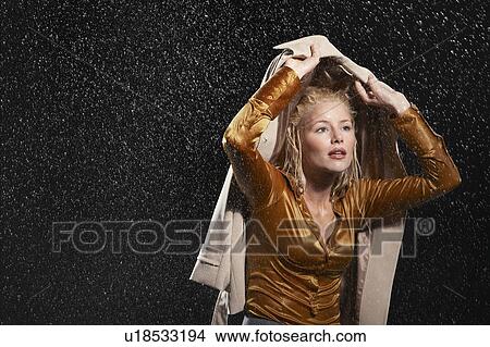 Businesswoman covering head with jacket during rainstorm View Large Photo Image Picture - Businesswoman covering head with jacket during rainstorm. Fotosearch