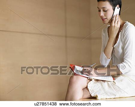 Businesswoman on cell phone taking notes View Large Photo Image Stock Photo - Businesswoman on cell phone taking notes. Fotosearch