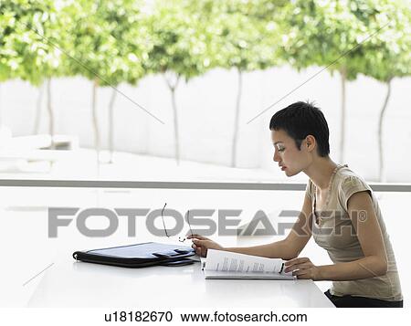 Businesswoman sitting in office looking at files View Large Photo Image Stock Image - Businesswoman sitting in office looking at files. Fotosearch