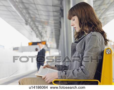 Businesswoman sitting on bench, reading a book at Train Station, side view View Large Photo Image Picture - Businesswoman sitting on bench, reading a book at Train Station, side view. Fotosearch