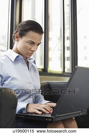 Stock Photography - Businesswoman sitting on sofa using laptop. Fotosearch