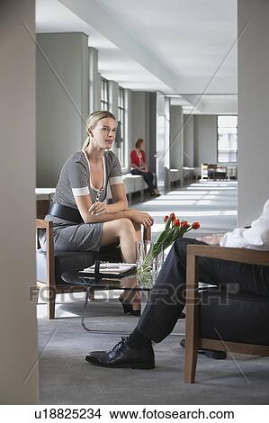 Picture - Businesswoman sitting, talking to businessman in office. Fotosearch