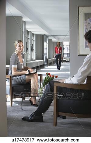 Stock Photo - Businesswoman sitting talking to businessman in office. Fotosearch