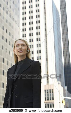 Businesswoman using wireless headset outdoors View Large Photo Image Stock Image - Businesswoman using wireless headset outdoors. Fotosearch