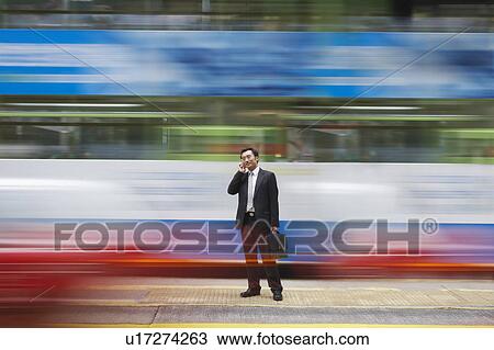 China, Hong Kong, business man using mobile phone, standing on street, long exposure View Large Photo Image Stock Image - China, Hong Kong, business man using mobile phone, standing on street, long exposure. Fotosearch