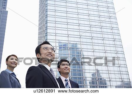 China, Hong Kong, three business people standing amongst skyscrapers, low angle view View Large Photo Image Stock Image - China, Hong Kong, three business people standing amongst skyscrapers, low angle view. Fotosearch