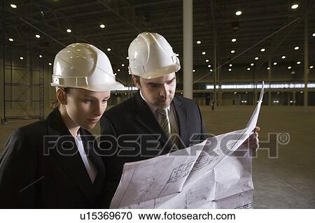 Colleagues study blueprint in empty warehouse View Large Photo Image Stock Image - Colleagues study blueprint in empty warehouse. Fotosearch