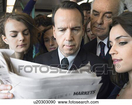 Commuters standing on train, reading newspaper over shoulder View Large Photo Image Stock Image - Commuters standing on train, reading newspaper over shoulder. Fotosearch