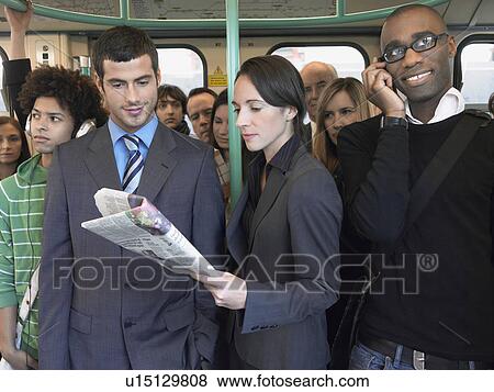 Commuters standing on train, reading newspapers, talking on mobiles View Large Photo Image Stock Photo - Commuters standing on train, reading newspapers, talking on mobiles. Fotosearch